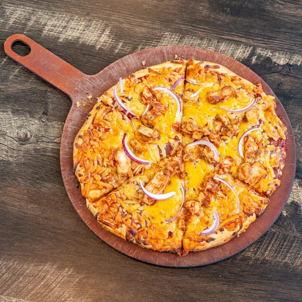 Invictus Pizza Kitchen's BBQ chicken pizza with red onions on a wooden serving paddle.