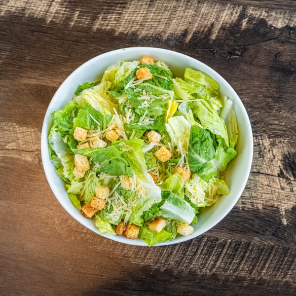 Invictus Pizza Kitchen's fresh Caesar salad with crisp romaine, croutons, and shredded Parmesan cheese.