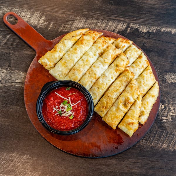 Invictus Pizza Kitchen's garlic knots, golden brown and served with a side of marinara sauce.